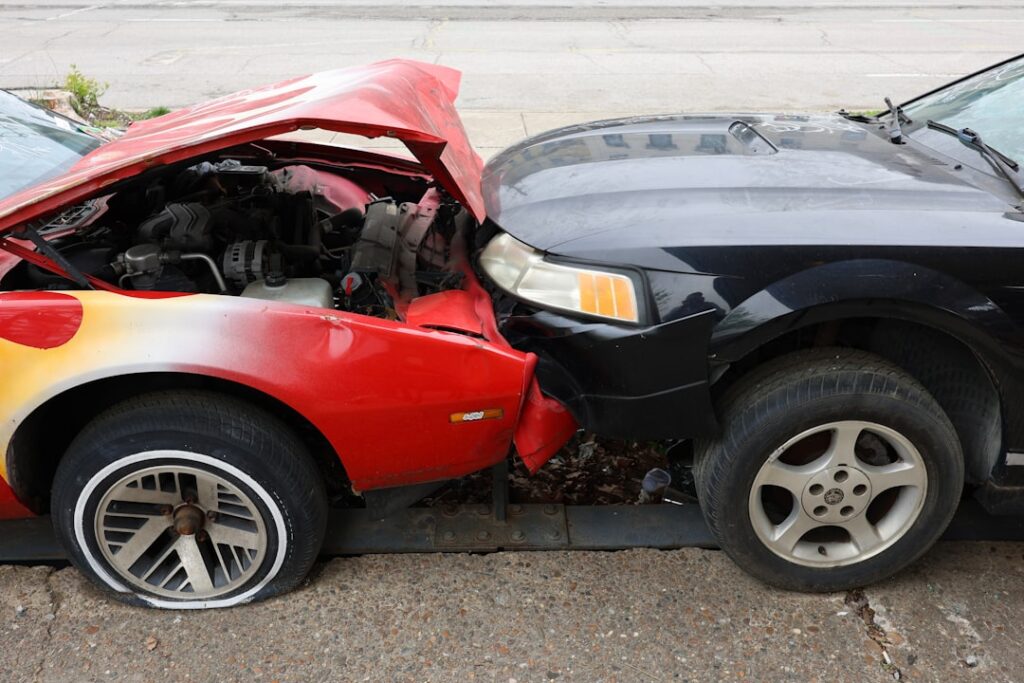 A driver taking photos of vehicle damage on a neighborhood street after a fender-bender.